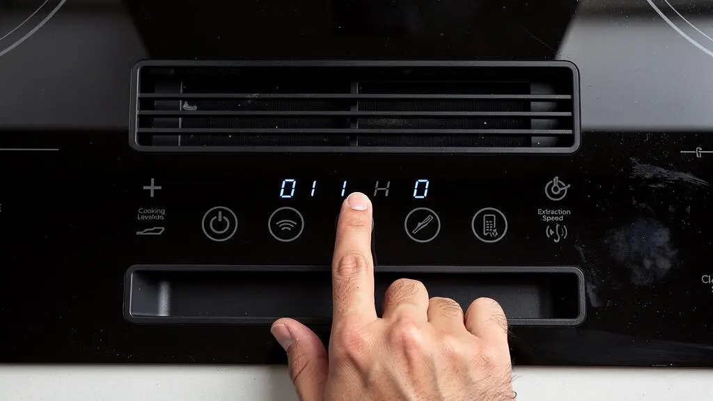 Vue détaillée du panneau de commandes tactile d'une plaque induction avec hotte intégrée montrant les zones de cuisson et les réglages d'aspiration